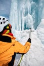 Woman climber with ice axe near frozen waterfall