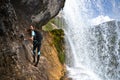 Woman climber on rock by waterfall