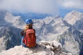 Woman climber sits at the edge of a rock in Triglav mountains, Slovenia, on a bright Summer day. Royalty Free Stock Photo