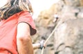 Woman climbing up on mountain cliff while man helping her to climb to the top holding the rope - Climber in action on the rock Royalty Free Stock Photo