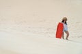 Woman climbing up a sand dune with a sandboard Royalty Free Stock Photo