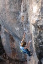 A woman climbs a rock