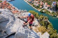 Woman climbs via ferrata Fortica above Cetina river and Omis city, Croatia. Climber, vertical, adventure, active, summer, tourism