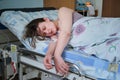 Woman on clinic bed with anesthesia at the time of labor pains. A pregnant woman gives birth in a hospital with a drip and a Royalty Free Stock Photo