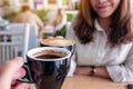 A woman clinking coffee mugs to a man in cafe Royalty Free Stock Photo