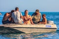 Woman with closed eyes gets sun, relax and enjoy. People in a small motorboat set off for a seaside boat trip