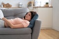 Woman with closed eyes lying on pillow resting trying to sleep in uncomfortable pose on sofa at home