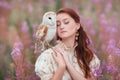 Woman closed eyes with owl on her shoulder.