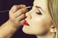 Woman with closed eyes and red lips getting makeup Royalty Free Stock Photo