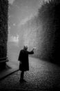 Woman in a coat, in an ancient public garden in a thick fog.