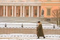 Woman in a coat with a fur collar walking along the snowy embankment