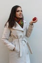 Woman in a coat holding a bitten red juicy apple