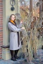 A woman in a coat stands near a decorative composition made of dry cane Royalty Free Stock Photo