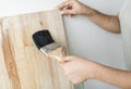 Woman coating a wooden plank with lacquer