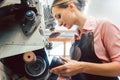 Woman cobbler working on machine in her shoemaker workshop