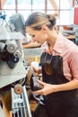 Woman cobbler working on machine in her shoemaker workshop