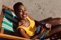 Woman with cocktail glass relaxing in a beach chair on the beach