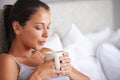 Woman, coffee and bed for relax in morning for wakeup and drink in cup for warm and steam with pillow. Young person with Royalty Free Stock Photo