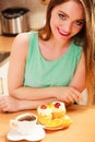 Woman with coffee and cake in kitchen. Gluttony.