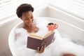 Woman with coffee cup reading book in a bathtub Royalty Free Stock Photo