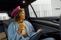 Woman with coffee and digital tablet on backseat of a car Royalty Free Stock Photo