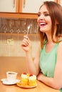 Woman with coffee eating cream cake. Gluttony.