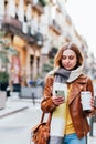 Woman with coffee surfing smartphone on street