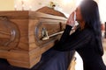 Woman with coffin crying at funeral in church Royalty Free Stock Photo