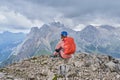 Woman on Colac peak, at the end of via ferrata dei Finanzieri, with helmet on and a backpack with rain cover, enjoys the panorama