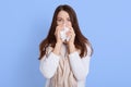 Woman with cold blowing her runny nose with tissue, Caucasian beautiful girl get sick sneezing from flu, lady wearing white Royalty Free Stock Photo