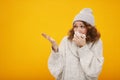 Woman with a cold blowing her runny nose with tissue holding your product. Portrait of beautiful girl in winter sweater and hat Royalty Free Stock Photo