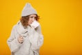 Woman with a cold blowing her runny nose with tissue. Portrait of beautiful girl in winter sweater and hat get sick sneezing from Royalty Free Stock Photo