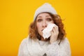 Woman with a cold blowing her runny nose with tissue. Portrait of beautiful girl in winter sweater and hat get sick sneezing from Royalty Free Stock Photo