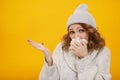 Woman with a cold blowing her runny nose with tissue. Portrait of beautiful girl in winter sweater and hat get sick sneezing from Royalty Free Stock Photo