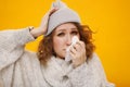 Woman with a cold blowing her runny nose with tissue. Portrait of beautiful girl in winter sweater and hat get sick sneezing from Royalty Free Stock Photo