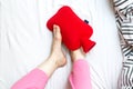 Woman with cold feet in bed on a red hot water bottle Royalty Free Stock Photo