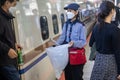 A woman collecting garbage at a railway station in Japan, next to a train car