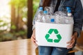 A woman collecting and holding a recyclable garbage plastic bottles into a trash bin