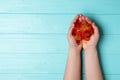 Woman with colorful jelly bears on wooden background, top view