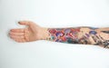 Woman with colorful tattoos on arm against background, closeup Royalty Free Stock Photo