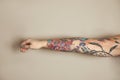 Woman with colorful tattoos on arm against background, closeup Royalty Free Stock Photo