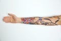 Woman with colorful tattoos on arm against background, closeup Royalty Free Stock Photo
