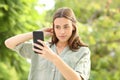 Woman combing hair using smartphone as a mirror Royalty Free Stock Photo