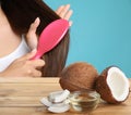 Woman combing her healthy hair and natural coconut oil on wooden table Royalty Free Stock Photo