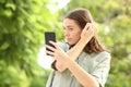 Woman combing using phone as a mirror in a park Royalty Free Stock Photo