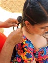 Woman combs her hair on the beach, pays to have braids made, a traditional tourist hairstyle in Acapulco Mexico