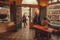 Woman come in old bar with some drinking men, sitting near window