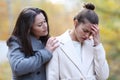 Woman comforting her sad friend in a park in winter Royalty Free Stock Photo