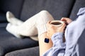 Woman in comfy warm socks drinking cup of tea in winter. Home comfort and relaxed morning on weekend. Trendy fashion style. Royalty Free Stock Photo