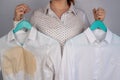 A woman compares two white shirts before and after washing. The girl is holding one blouse, clean and ironed, and the Royalty Free Stock Photo